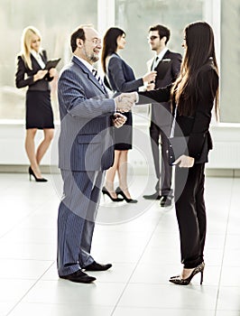 Welcome handshake Manager and client on the background of business team