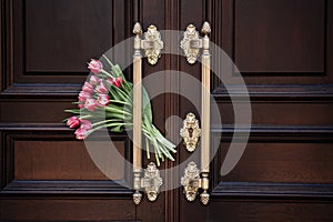 Welcome and Hospitality. Tulips bouquet Beside Ornate Wooden Door Welcome Symbol. The flowers next to a door symbolize a
