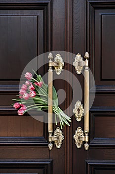 Welcome and Hospitality. Tulips bouquet Beside Ornate Wooden Door Welcome Symbol. The flowers next to a door symbolize a