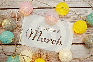 Welcome March card typography text with LED cotton ball on wooden background