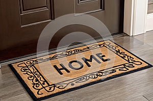 A welcome mat in front of a door that says word text HOME