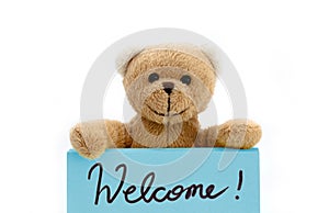 Welcome message from brown teddy bear holding with the two hands a note in blue color with the handwritten message