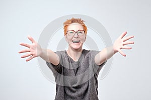 Welcome or Nice to meet you concept. European woman in gray sweater and glasses with stretched hands handshake.