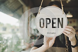 Welcome. Open. barista, waitress woman turning open sign board on glass door in modern cafe coffee shop