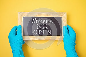 Welcome we are open sign in hands with blue medical gloves. Cafe, restaurant and store reopen after COVID -19 coronavirus pandemic