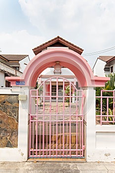 Welcome pink gate, pink fence white wall stone wall. house in the village