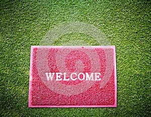 Welcome Red Mat on green grass .