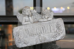 Welcome sign on stone against glass door of restaurant