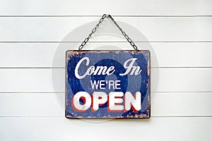 Welcome Sign with text & x22;COME IN WE& x27;RE OPEN& x27; hanging on wood white wall