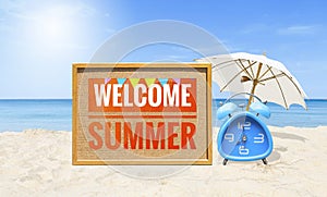 Welcome summer sign with blue alarm clock and white umbrella on tropical beach