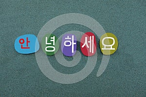 Welcome text in Korean language with a composition of handmade colored stone letters over green sand