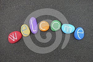 Welcome text with multi colored stones over black volcanic sand