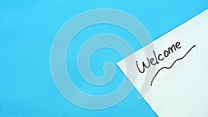 Welcome text on white paper with blue background copy space.