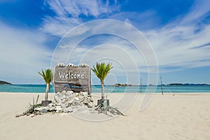 Welcome text on wooden sign on the beach