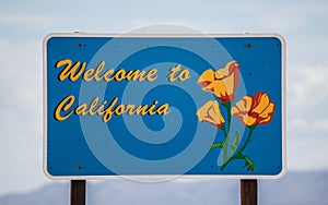 Welcome to California state sign in the foreground of a scenic highway, USA