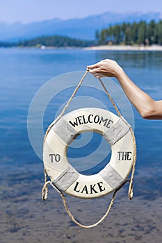 Welcome to the lake. Old lifebuoy on a rope with a beautiful blue Mountain lake in the background.