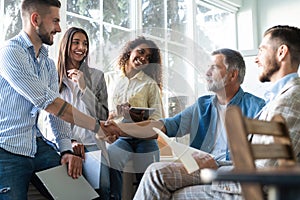 Welcome to our team! Business men in smart casual wear shaking hands while working in the creative office.