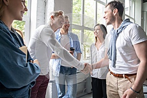 Welcome to our team! Business men in smart casual wear shaking hands while working in the creative office.