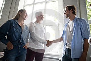 Welcome to our team! Business men in smart casual wear shaking hands while working in the creative office.