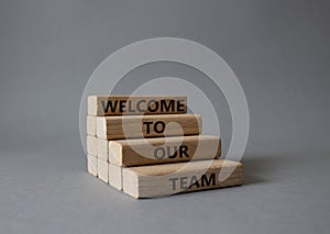 Welcome to our team symbol. Concept words Welcome to our team on wooden blocks. Beautiful grey background. Business and Welcome to