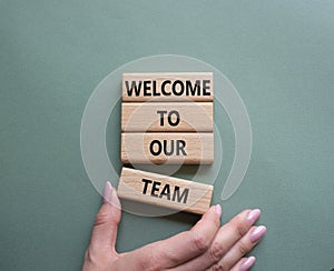 Welcome to our team symbol. Concept words Welcome to our team on wooden blocks. Beautiful grey green background. Businessman hand