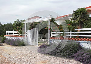 Welcome to relax in a cozy place. White fence and open gate.
