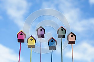 Welcome to the spring garden birds to a group of colorful wooden birdhouses on a blue sky background