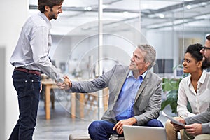 Welcome to the team young man. Shot of a two business professionals shaking hands in an office.
