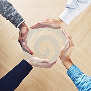 Welcome to the world of business. High angle shot of a group of unidentifiable businesspeople forming a circle with