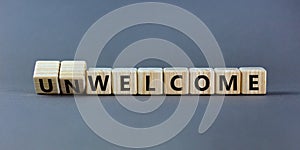 Welcome or unwelcome symbol. Turned wooden cubes and changed the word unwelcome to welcome. Beautiful grey table, grey background