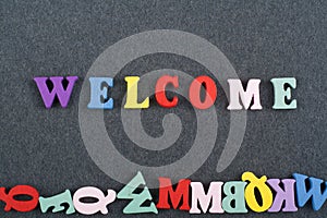 WELCOME word on black board background composed from colorful abc alphabet block wooden letters, copy space for ad text. Learning