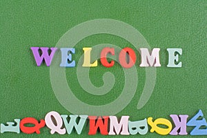 WELCOME word on green background composed from colorful abc alphabet block wooden letters, copy space for ad text. Learning