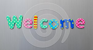 Welcome word spelled out in bright colorful patterened letters on brushed metal background