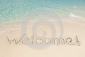 Welcome written on sand by sea