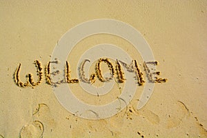 Welcome written in a sandy