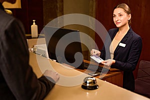 Welcoming administrator staying at counter and puts keycard in holder