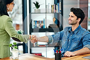 Welcoming a new member to the team. two businesspeople shaking hands in an office.