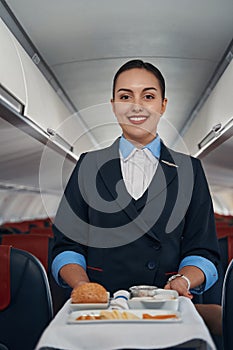 Welcoming stewardess pushing meal trolley inside plane