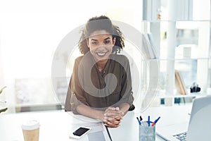Welcoming you to another year of success and prosperity. Portrait of a confident young businesswoman sitting at her desk