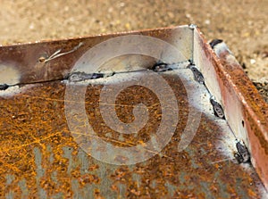 Weld seams on rusty metal. The metal corner is welded to the iron base