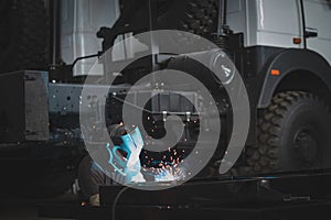 Welder in a car workshop welds a truck frame photo