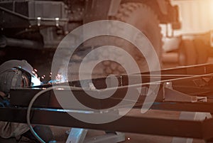 Welder in a car workshop welds a truck frame photo