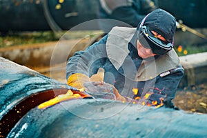 The welder cuts large metal pipes with ocetylene welding.