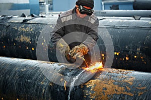 The welder cuts large metal pipes with ocetylene welding.