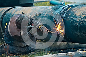 The welder cuts large metal pipes with ocetylene welding.