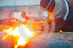 The welder cuts large metal pipes with ocetylene welding.