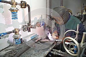 Welder electric arc welding using personal protective equipment, boiler room.