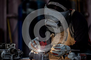 Welder in face mask welds with argon arc stainless steel welding, Industrial worker at the factory welding steel structure, Welder