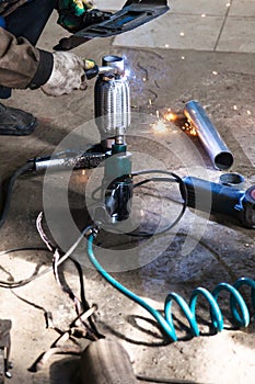 Welder fixes pipe on corrugation muffler photo