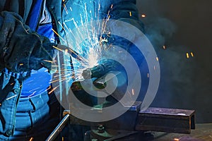 Welder in gloves welds a metal part in the factory.8